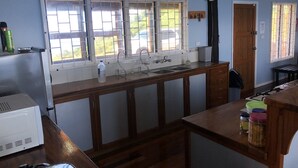 A kitchen with wooden cabinets, a sink, and a window with a view of the outside. - Over the Horizon near Savusavu Market (Savusavu)