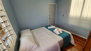A bedroom with a bed, a door, and a window with blinds. - Over the Horizon near Savusavu Market (Savusavu)