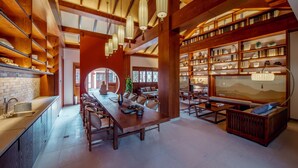 A spacious library with wooden bookshelves, a long dining table, and hanging lanterns. - Grand House Chongqing (Chongqing)