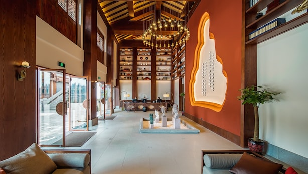 A spacious lobby with a high ceiling, wooden beams, and a central chandelier. There are seating areas with cushions and a coffee table. - Grand House Chongqing (Chongqing)