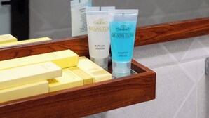 A bathroom vanity with toiletries including bath gel, shampoo, and cotton pads.