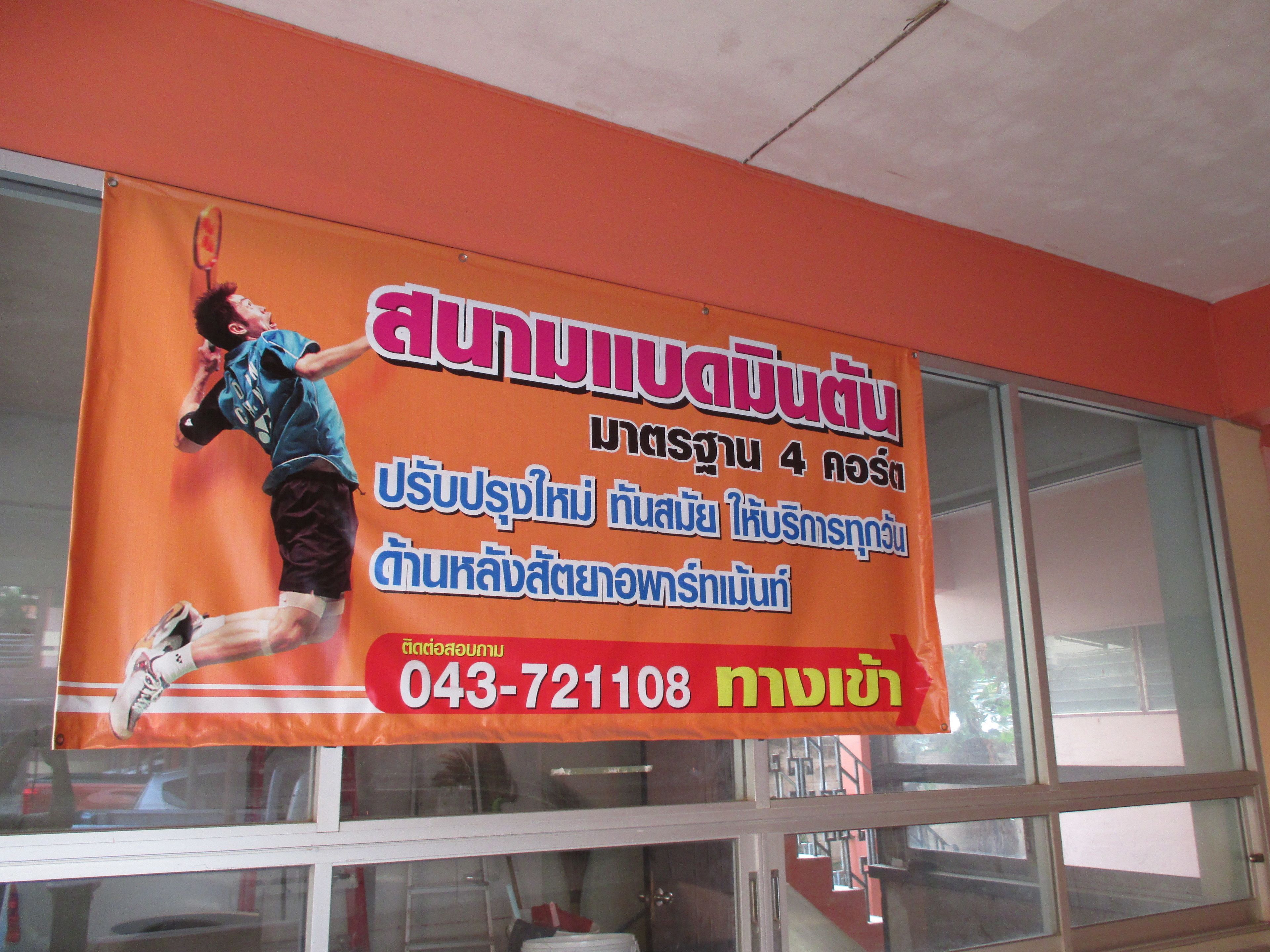 A banner with Thai text and a tennis player illustration, a contact number, and a window with reflections.