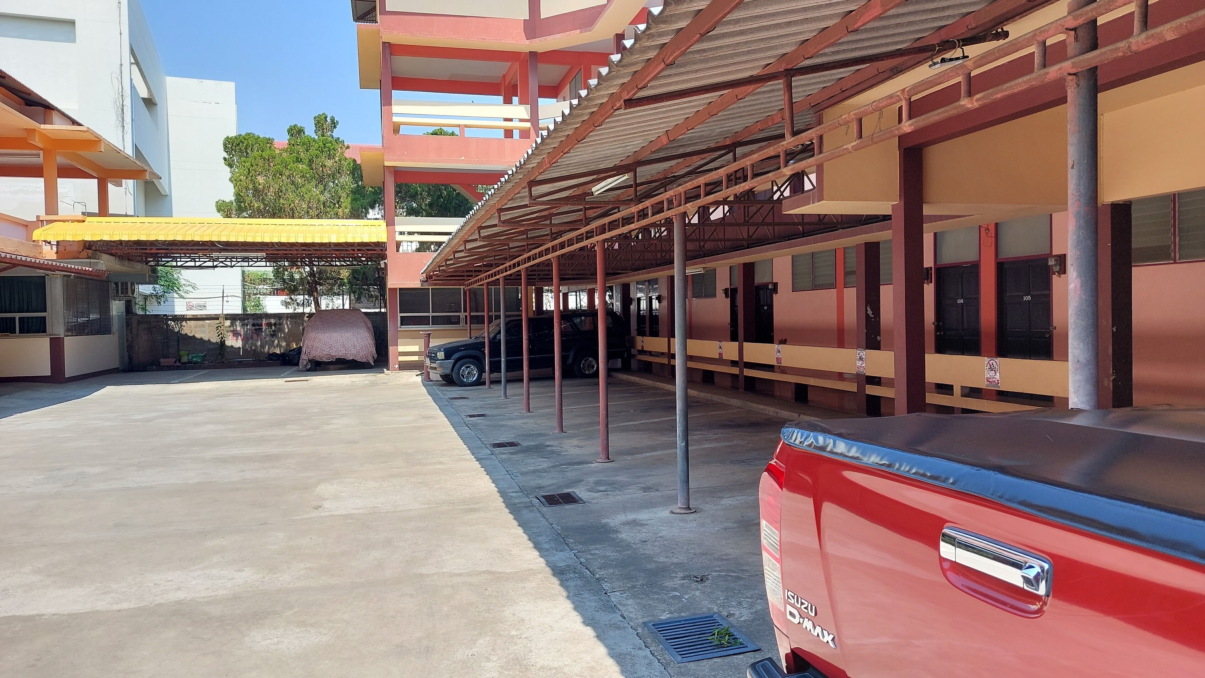 A covered parking area with a red car parked in the foreground.