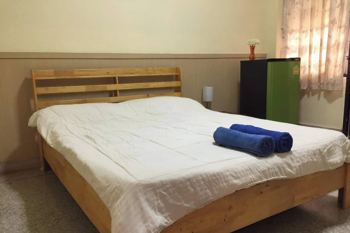 A single bed with a wooden frame, white bedding, and blue towels.