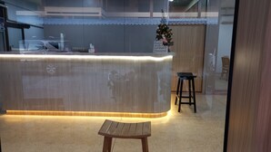 A reception area with a wooden counter, a small stool, and a Christmas tree. - Sataya Apartment (Maha Sarakham)