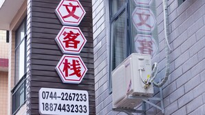 A hotel sign with Chinese characters and contact numbers.
