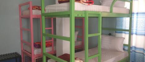 Bunk beds with pillows and blankets, a tiled floor, and a window with curtains.