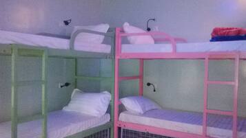 Two bunk beds with white bedding and pink railings, each with a small shelf and a hanging light.