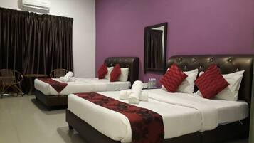 A hotel room with two beds, purple walls, a mirror, and a window with curtains.