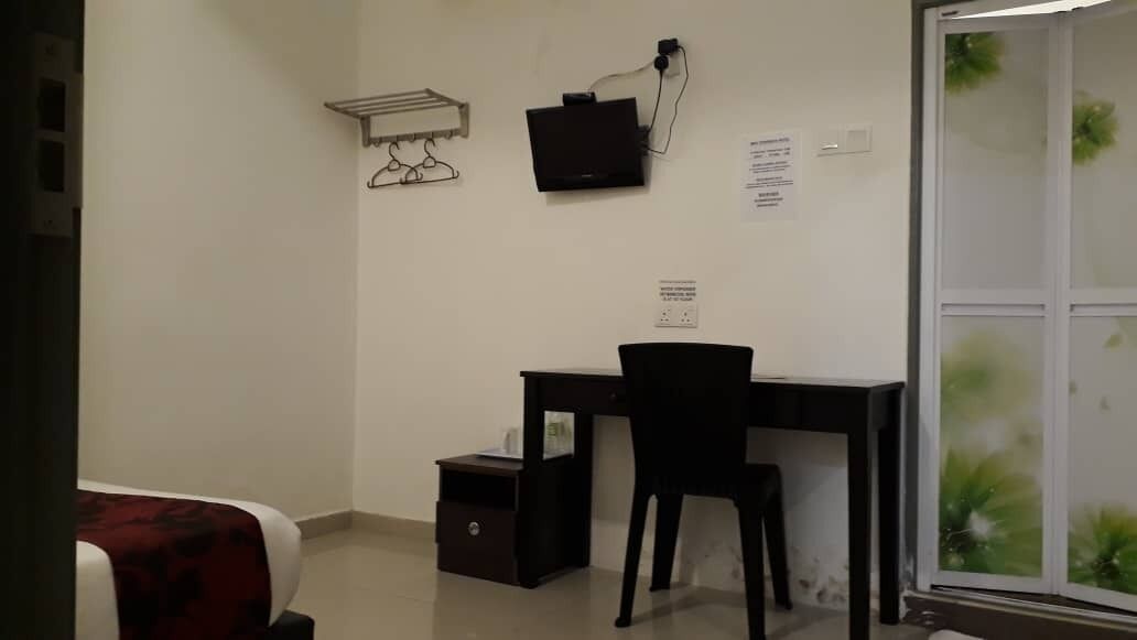Quarto com escrivaninha, cadeira e pequena mesa de cabeceira. Janela com vista para o verde.