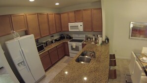 A modern kitchen with granite countertops, stainless steel appliances, and wooden cabinets. - Aco63675 - Bella Vida Resort - 4 Bed 3 Baths Townhouse (Kissimmee)