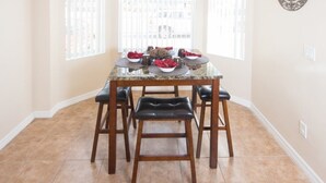 Un comedor con una mesa dispuesta para cuatro personas, rodeada de sillas de madera.