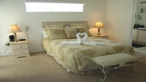 Une chambre à coucher bien rangée, avec un lit, deux tables de chevet, des lampes, une radio sur la table de chevet et une fenêtre.