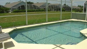 Une piscine rectangulaire dont les bords sont recouverts de carreaux, entourée d’une clôture blanche.