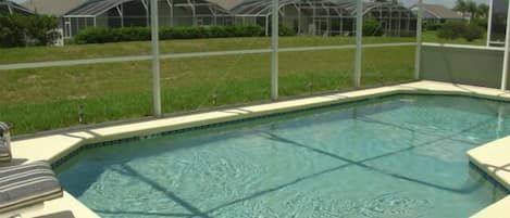 A rectangular swimming pool with a tiled edge, surrounded by a white fence.