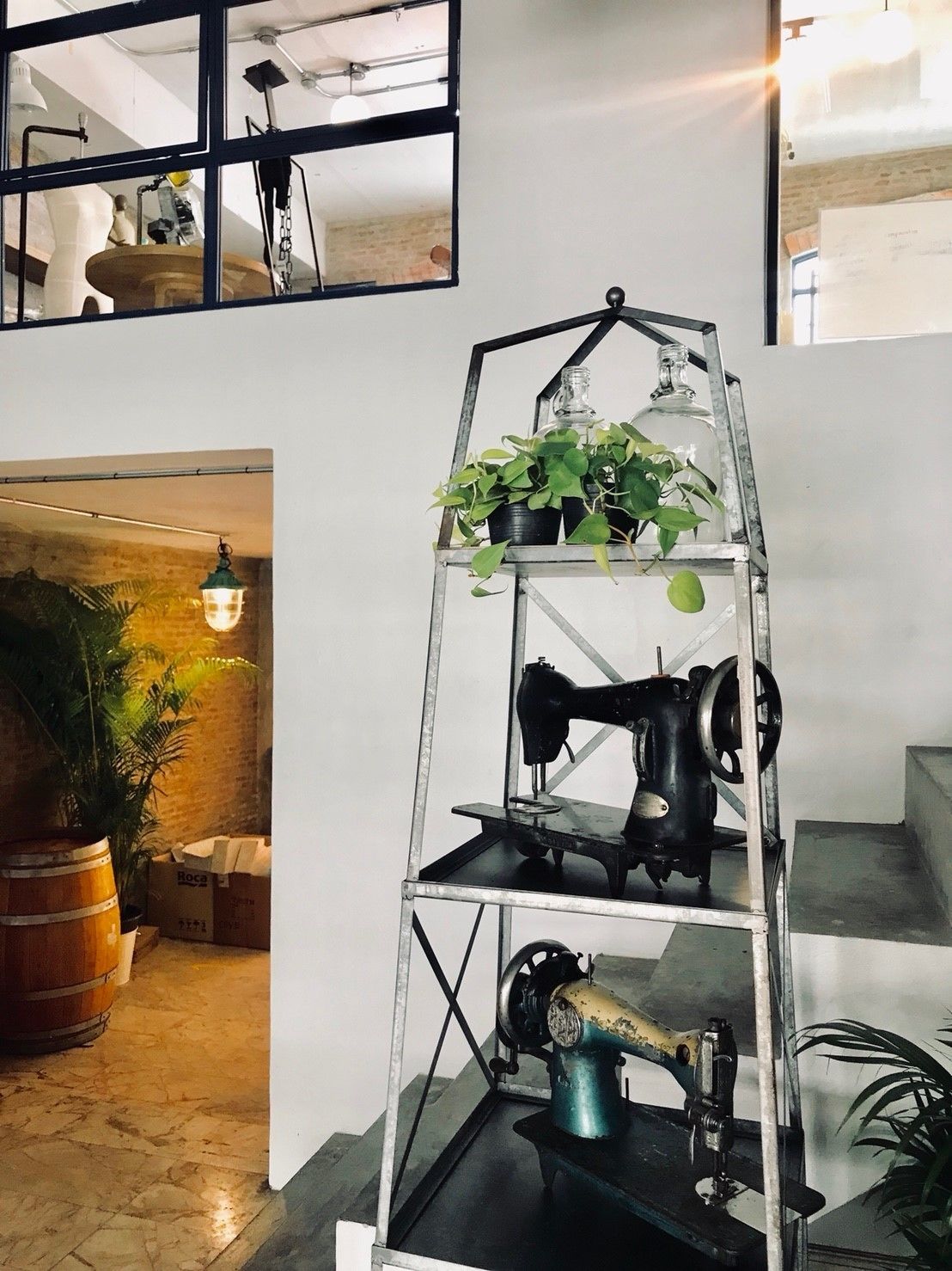 A metal shelving unit with sewing machines and a potted plant.