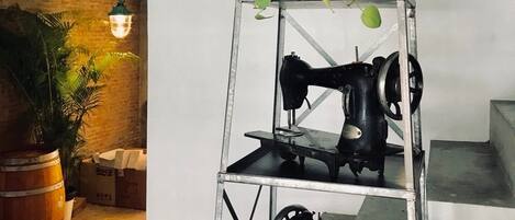 A metal shelving unit with sewing machines and a potted plant.