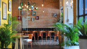 Un restaurant aux murs de briques, aux luminaires suspendus, aux tableaux encadrés et aux chaises en bois.