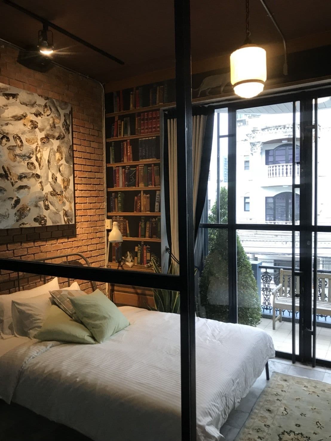 Une chambre avec un grand lit, une bibliothèque et une vue sur l’extérieur.