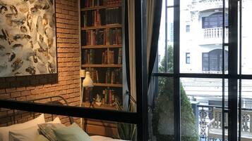 Une chambre avec un grand lit, une bibliothèque et une vue sur l’extérieur.