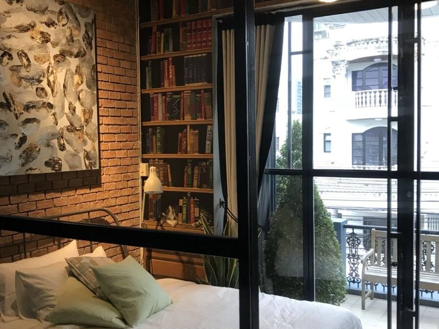 Une chambre avec un grand lit, une bibliothèque et une vue sur l’extérieur.