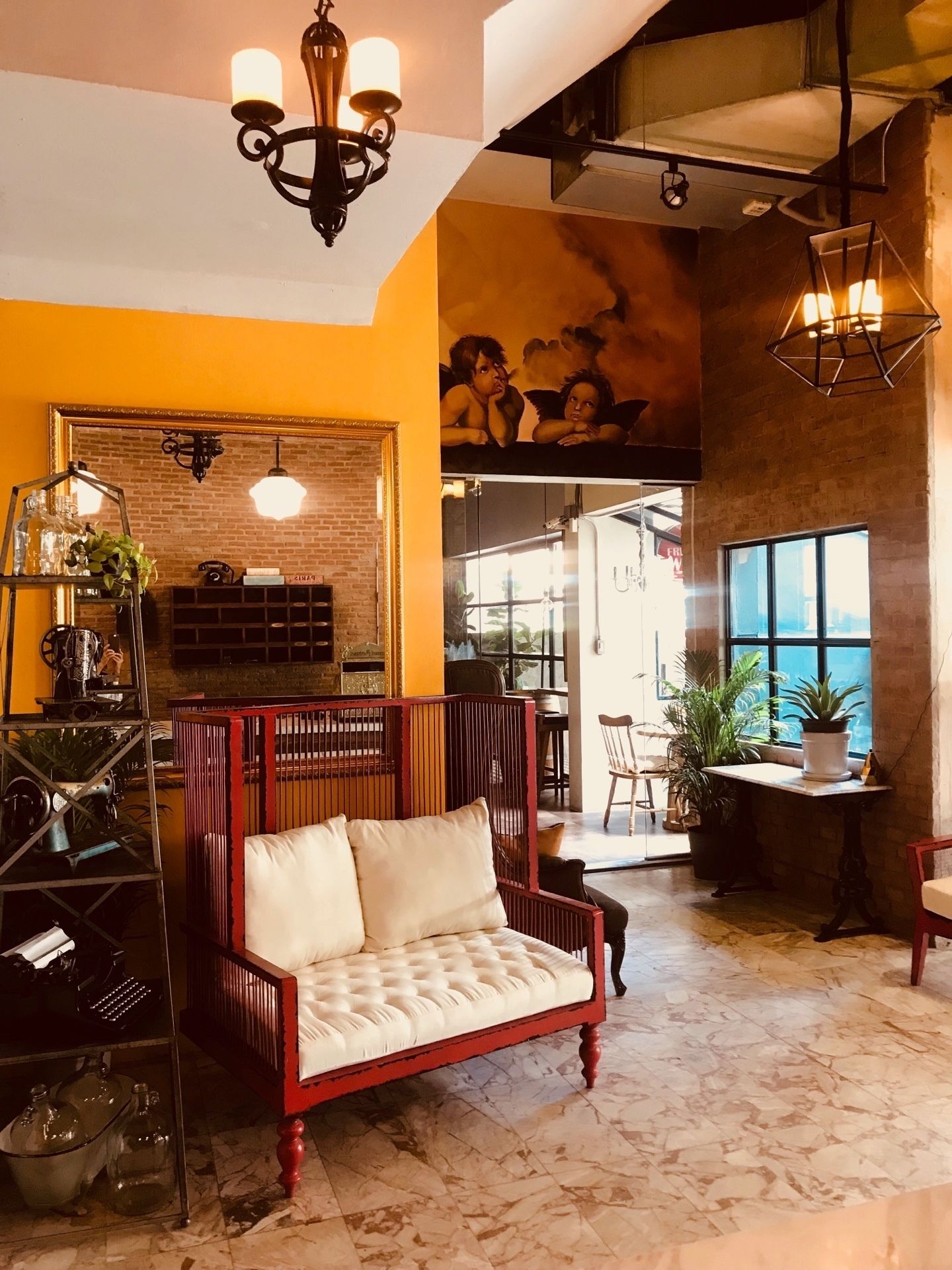A cozy lounge area with a cushioned bench, a metal shelving unit, and a brick wall with a mural.