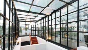 Un intérieur moderne avec un plafond en verre, un escalier en bois et une vue sur le paysage urbain.