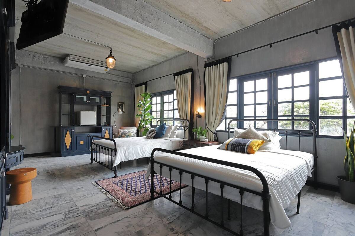 Une chambre avec deux lits, un bureau et une grande fenêtre.