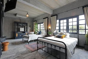 A bedroom with two beds, a desk, and a large window.