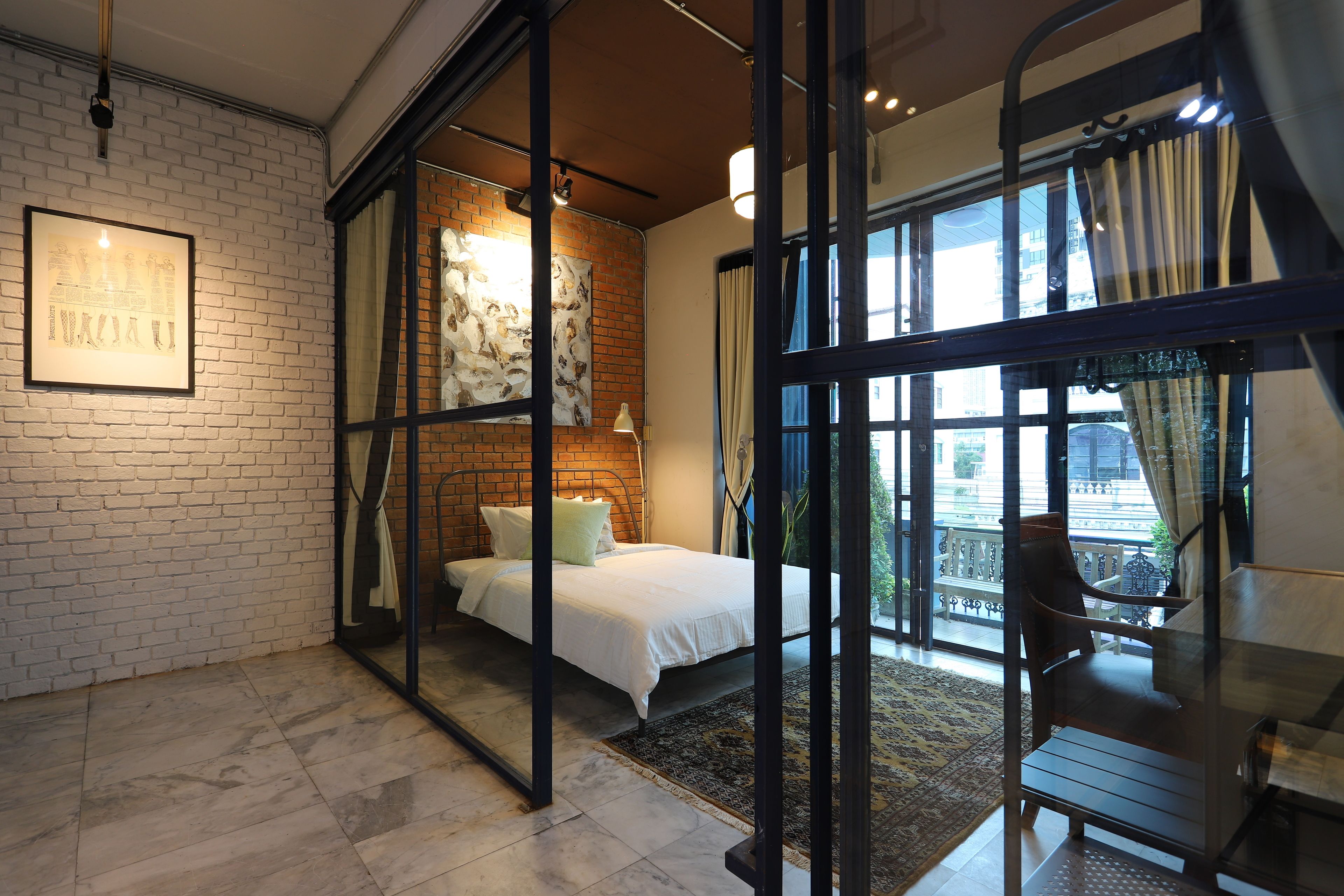 Quarto com cama, escrivaninha, cadeira e vista para o exterior.