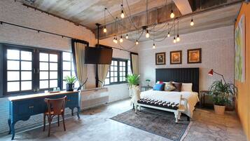 A bedroom with a bed, desk, chair, and potted plants.