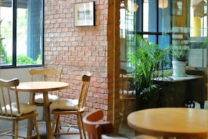 A cafe with brick walls, wooden chairs, and tables.