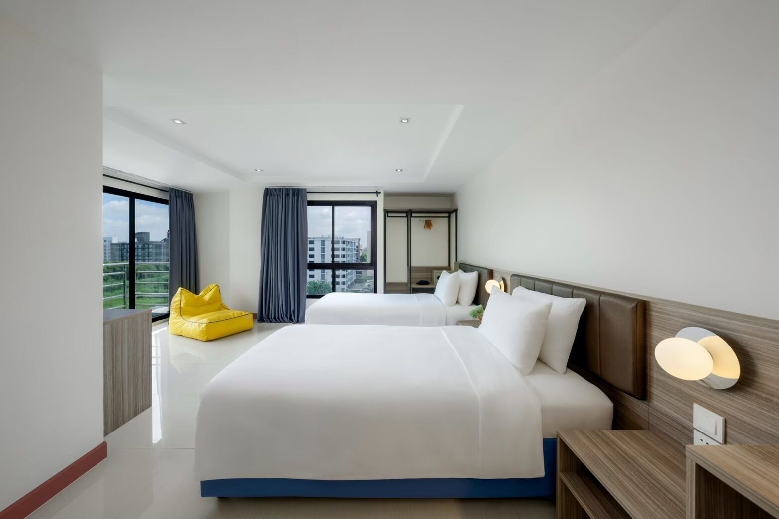 Habitación de hotel moderna con una cama grande, un escritorio pequeño, una silla y vistas a la ciudad.