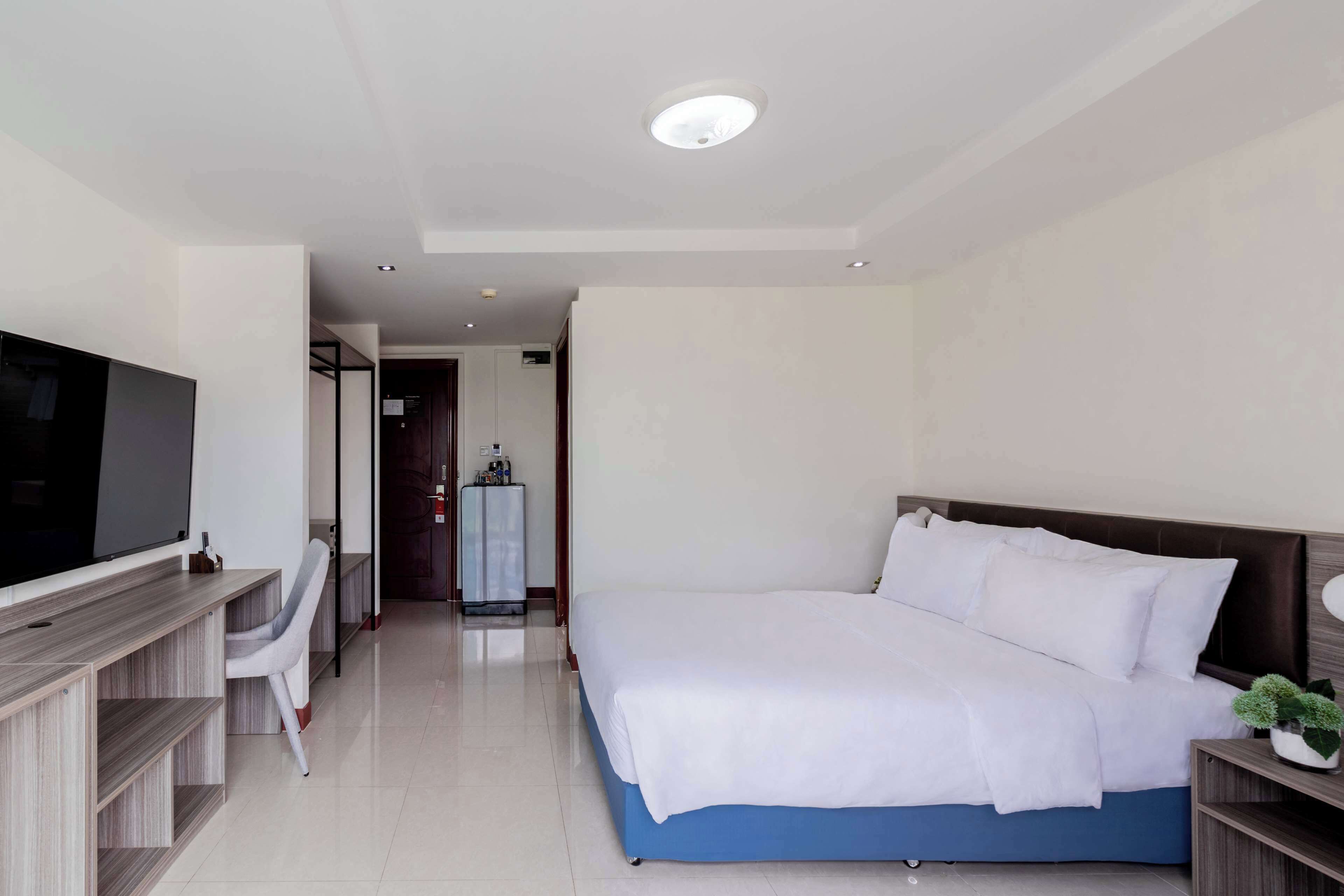 A hotel room with a bed, a TV, a desk, and a chair.