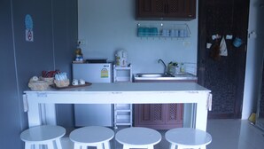 A kitchen with a white countertop, three white stools, a refrigerator, a sink, and cabinets. - 5 Min Ninman Road & Best Mountain View (Chiang Mai)