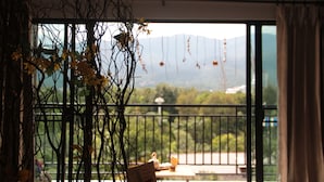 A balcony with a view of mountains, a table, and chairs. - 5 Min Ninman Road & Best Mountain View (Chiang Mai)