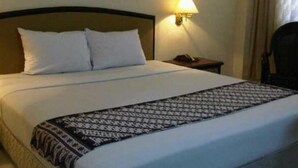 Una habitación de hotel con una cama bien hecha, una lámpara de noche y una mesita.