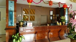 Un área de recepción con un mostrador de madera, plantas en macetas y decoración tradicional.