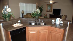 A kitchen with granite countertops, a dishwasher, wooden cabinets, a sink, and a ceiling fan. - Ip60215 - Sand Hill - 5 Bed 3 Baths Villa (Davenport)