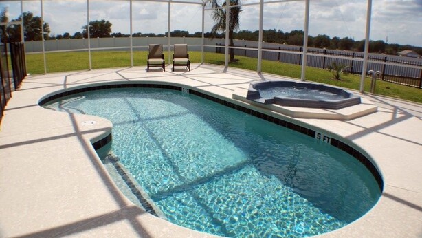A swimming pool with a hot tub, two lounge chairs, and a view of a grassy area and fence. - Ip60215 - Sand Hill - 5 Bed 3 Baths Villa (Davenport)