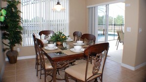 A dining area with a wooden table set for four, surrounded by chairs, a hanging light fixture, and a potted plant. - Ip60215 - Sand Hill - 5 Bed 3 Baths Villa (Davenport)