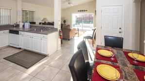 A spacious kitchen with white cabinets, a granite countertop, and a dining area with a table set for four. - Ip60224 - Rolling Hills Estates - 4 Bed 3 Baths Villa (Kissimmee)