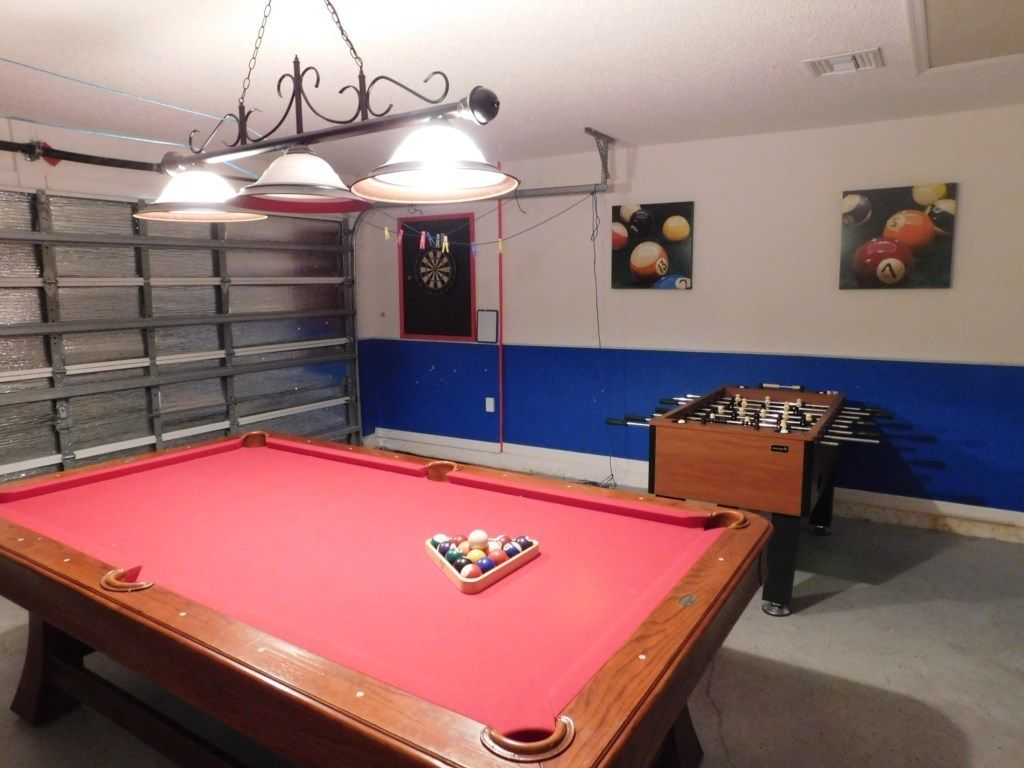 Ein Billardtisch mit roter Spielvliesbahn, ein Kicker und eine Dartscheibe.