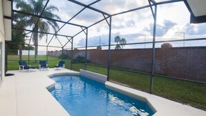 A swimming pool with a glass enclosure, surrounded by a brick wall and a grassy area. - Ip60224 - Rolling Hills Estates - 4 Bed 3 Baths Villa (Kissimmee)