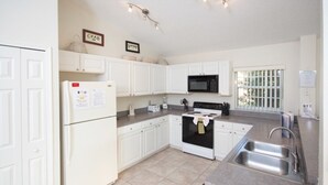 A kitchen with white cabinets, a refrigerator, a microwave, an oven, and a sink. - Ip60224 - Rolling Hills Estates - 4 Bed 3 Baths Villa (Kissimmee)