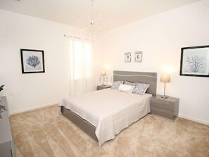 A bedroom with a bed, bedside tables, and wall art.