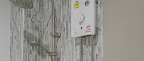 A shower with a control panel, a handheld showerhead, and a handheld shower attachment.