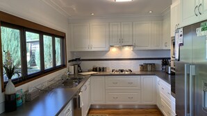 Eine moderne Küche mit weißen Schränken, einem Edelstahlkühlschrank und einem Fenster mit Blick auf Grünflächen.
