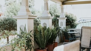 Eine Terrasse im Freien mit Blumentöpfen, einem Tisch und Stühlen.
