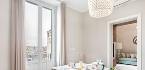 A modern dining area with a marble table, white chairs, and a bowl of fruit. - Riva Sea View Apartment by Wonderful Italy (Siracusa)